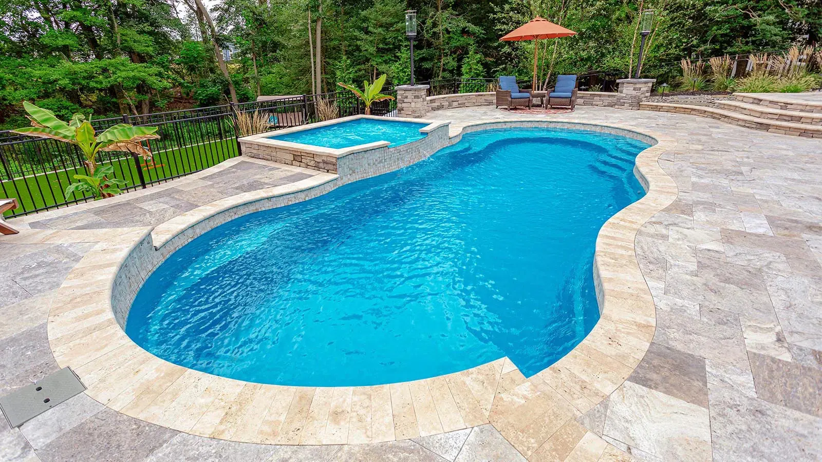 Curved swimming pool with adjacent hot tub.