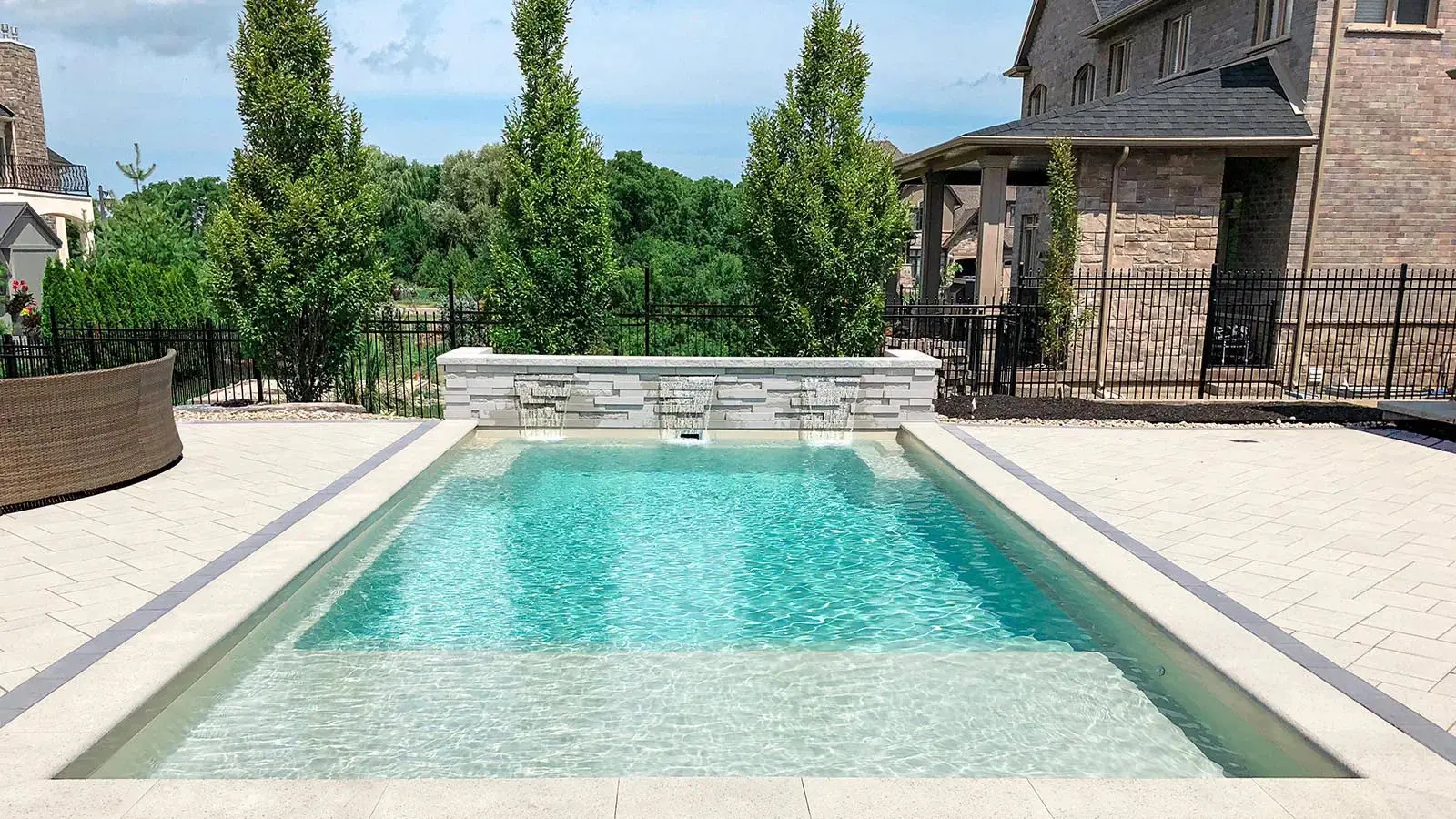 Backyard pool with trees and house.