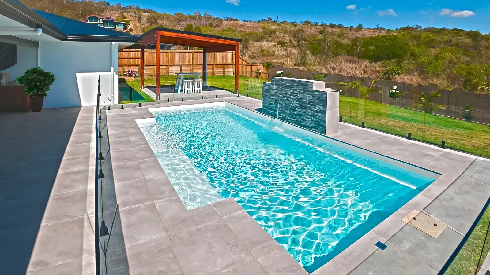Modern backyard swimming pool with patio area.