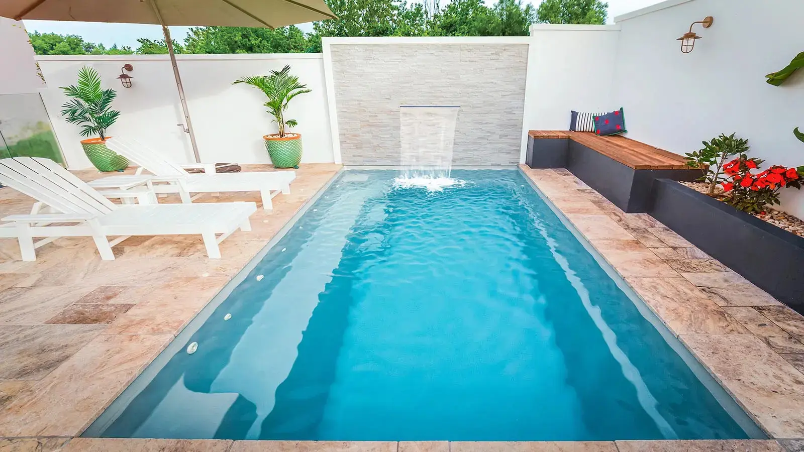Small backyard pool with lounge chairs.